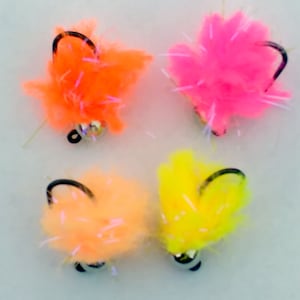 May include: Four colorful fluffy fishing lures with a hook and a bead. The lures are orange, pink, yellow, and peach.