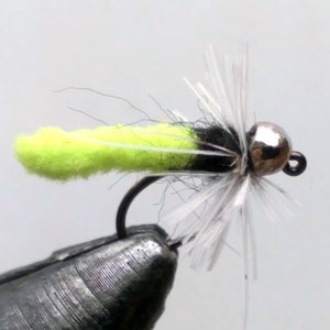 May include: A close-up of a fly fishing lure with a bright yellow body, black hackle, and white marabou feathers. The lure has a silver bead head and is tied on a hook.