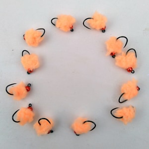 May include: A collection of 10 orange fuzzy fishing flies with black hooks and red beads.