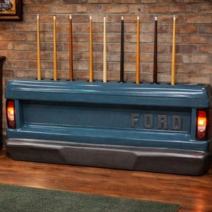 Op de afbeelding: Een blauwe Ford-vrachtwagenbak omgebouwd tot een keurek. De houder bevat verschillende keuen in verschillende kleuren. Het Ford-logo is zichtbaar. De houder heeft werkende achterlichten. De achtergrond is een bakstenen muur.