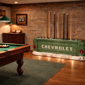 Op de afbeelding: Een biljartkamer met een groene Chevrolet-vrachtwagenbak die is omgebouwd tot een keurek. De kamer bevat een pooltafel, keuen en kunstwerken. De vrachtwagenbak heeft het woord "CHEVROLET" in witte letters.