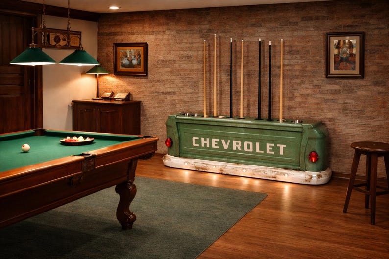 Op de afbeelding: Een biljartkamer met een groene Chevrolet-vrachtwagenbak die is omgebouwd tot een keurek. De kamer bevat een pooltafel, keuen en kunstwerken. De vrachtwagenbak heeft het woord "CHEVROLET" in witte letters.