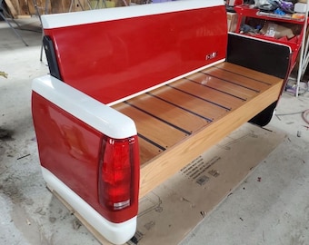 May include: A red and white truck bed converted into a bench with a wooden top and black accents.