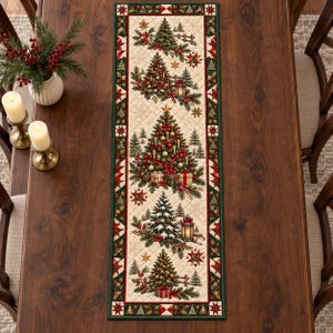 May include: A rectangular quilted table runner featuring a cream-colored center panel with a repeating pattern of decorated Christmas trees, lanterns, and wrapped gifts, bordered by a dark green frame with red and white geometric star accents.