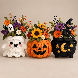May include: Three crocheted Halloween-themed planters filled with colorful yarn flowers and greenery. The left is a white ghost, the center is an orange jack-o'-lantern, and the right is a black cauldron decorated with a yellow moon and stars.