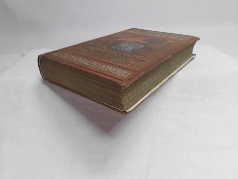 May include: A vintage book with a brown cover featuring an illustration and the title "The Motor Boys". The book's spine and pages are visible, with the author's name printed on the cover. The book is set against a white background.
