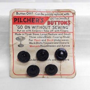 May include: Five black circular buttons attached to a vintage cardboard display card. The card features red and black text reading Pilcher's Detachable Buttons, Go On Without Sewing, and lists sizes and uses for underwear, shirts, and aprons.