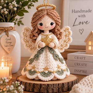 May include: A crocheted angel doll with light brown yarn hair, a gold halo, and white wings adorned with small pearls. The doll wears a white dress featuring green leaf accents, gold star embroidery, and a gold star held in its hands.