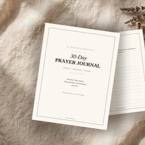Puede incluir: Un diario de oración de 30 días con una cubierta de color crema que presenta texto negro que dice My Prayerful Thoughts, 30-Day Prayer Journal, Scriptures, Declarations, Gratitude y texto adicional. El diario está abierto en una página rayada.