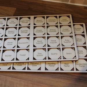 May include: A wooden board with 49 hexagonal spaces, each with a different label. The labels include "Stone Storage", "Ore Storage", "Spare Parts Storage", "Broem Chamber", "Treasure Chamber", "Food Chamber", "Main Storage", "Weapon Storage", "Supplies Storage", "Prayer Chamber", "Writing Chamber", "Fodder Chamber", "Stutible Room", "Carpenter", "Stone Carver", "Blacksmith", "Wood Supplier", "Stone Supplier", "Ruby Supplier", "Office Room", "Miner", "Builder", "Trader", "Dog School", "Quarry", "Seam", "State Parior", "Cave", "Breeding Cave", "Peaceful Cave", "Hunting Parlor", "Beer Parlor", and "Blacksmithing Parlor".