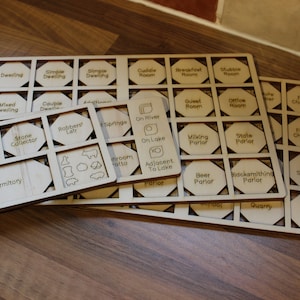 May include: Wooden game pieces with hexagonal shapes and various labels, including "Gazebo", "Dwelling", "Stone Collector", "Robbers' Lair", "Springs", "On River", "On Lake", "Milking Parlor", "State Parlor", "Guest Room", "Office Room", "Food Chamber", "Fodder Chamber", "Beer Parlor", "Blacksmithing Parlor", "Ruby Supplier", "Quarry", and "Seam".