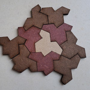 May include: A wooden puzzle with geometric shapes in brown and pink shades. The puzzle pieces fit together to form a larger shape.