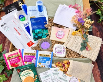 Può includere: Una confezione regalo contenente vari articoli tra cui maschere in tessuto Mediheal e JM Solution, bustine di tè Twinings, biscotti all'avena Walkers, una fascia bianca, una saponetta, una candela viola, una pastiglia doccia, fiori secchi e sali da bagno.