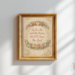 May include: Framed artwork with the text "As For Me and My House, We Will Serve The Lord." The artwork features a floral wreath design in pink, yellow, and blue, set against a cream-colored background. The frame is gold.
