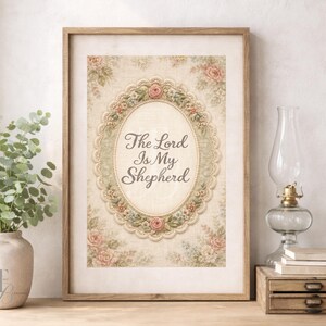 May include: A framed print with the text "The Lord Is My Shepherd" in an oval frame. The print has a floral design with pink roses and a beige background. The frame is made of light brown wood.
