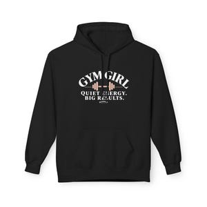 May include: A black hooded sweatshirt featuring a white graphic print on the chest. The text reads GYM GIRL with a barbell icon, followed by the text QUIET ENERGY. BIG RESULTS. and a small logo at the bottom. The hoodie has long sleeves.