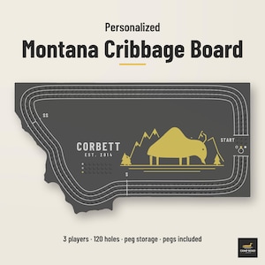 May include: A dark gray Montana-shaped cribbage board featuring a gold bison and mountain graphic. The board includes the text Corbett Est. 2014, Start, and SS. It is designed for 3 players with 120 holes, peg storage, and pegs included.