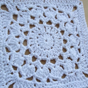 May include: White crocheted square with a detailed center pattern.
