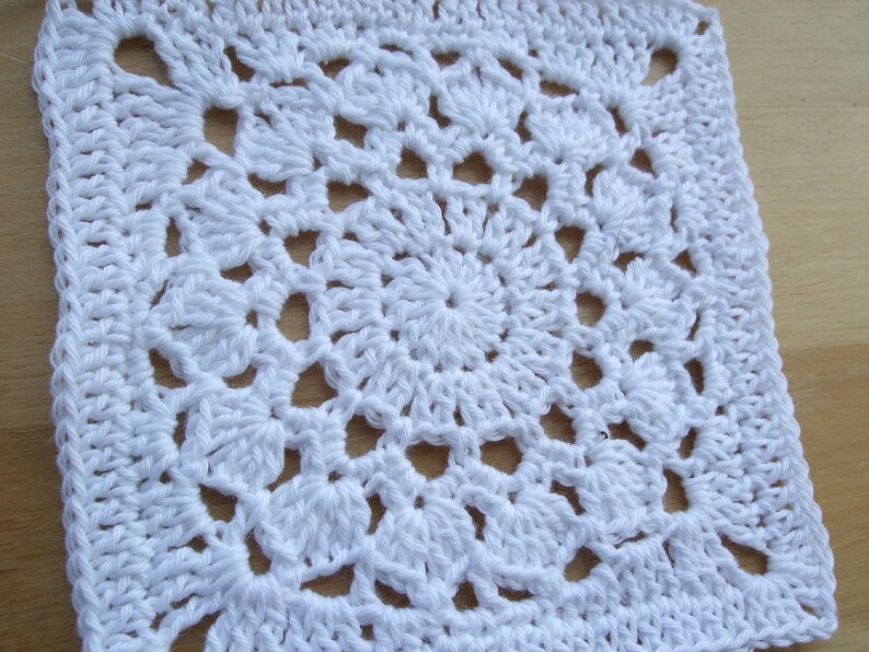 May include: White crocheted square with a detailed center pattern.
