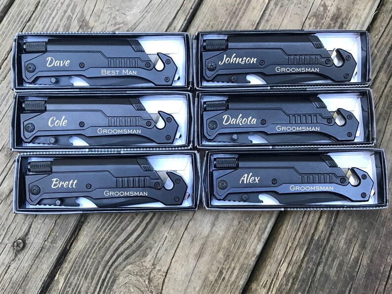 Puede incluir: Seis navajas de bolsillo negras con nombres personalizados y la palabra "Groomsman" grabada en cada una. Los nombres son Dave, Cole, Brett, Johnson, Dakota y Alex.