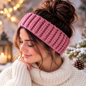 May include: A dusty rose pink knitted ear warmer headband featuring a thick, vertical ribbed texture. The accessory is crafted from a soft yarn material and is designed to be worn around the head to cover the ears, providing a cozy, textured look.