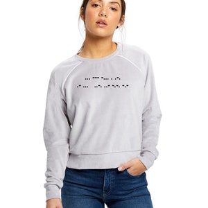 May include: A light gray sweatshirt with a black design of braille dots that spell out the word "LOVE".