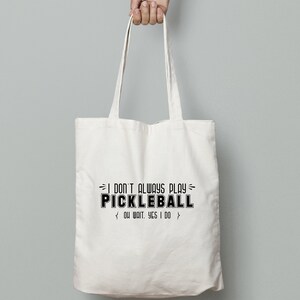 May include: White canvas tote bag with black text that reads "I don't always play pickleball. Oh wait, yes I do."