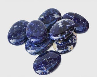 May include: A collection of seven polished, oval-shaped sodalite stones. Each stone features a deep royal blue base color with irregular, cloudy white mineral inclusions and veins distributed across their smooth, glossy surfaces.