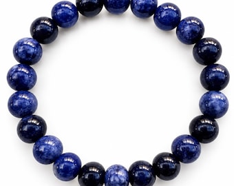 May include: A circular stretch bracelet composed of twenty-two polished, spherical beads. The beads feature varying shades of deep navy blue and royal blue, with some displaying a mottled, marbled texture and others appearing as solid, dark blue.