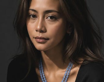 May include: A double-strand necklace featuring light blue, smooth, round beads and small silver-toned spacers. The necklace includes a circular silver-toned pendant engraved with a lotus flower design, resting against a plain black garment.
