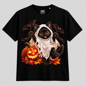Può includere: Una t-shirt nera a maniche corte con la grafica di un gattino nero che indossa un costume da fantasma bianco. Il gattino è circondato da tre piccoli pipistrelli, una zucca arancione luminosa e foglie autunnali colorate. Il marchio Mali è stampato sull'etichetta interna del collo.