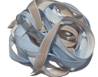 May include: A bundle of blue and beige ribbon with a textured surface. The ribbon is folded and twisted together.