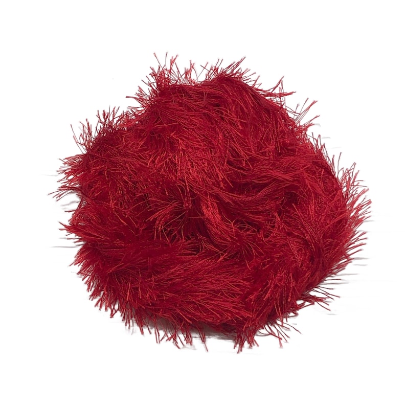 Puede incluir: Una madeja de hilo rojo vibrante con una apariencia difusa y texturizada. El hilo est&aacute; densamente empaquetado, creando un aspecto suave y afelpado. El color rojo brillante es consistente, adecuado para varios proyectos de manualidades.