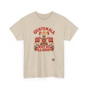 Puede incluir: Una camiseta beige de manga corta con un gr&aacute;fico de dos llamas, un sol y motivos florales. El texto GUATEMALA WHY NO LLAMA? aparece en letras rojas. Un peque&ntilde;o c&oacute;digo QR cuadrado est&aacute; impreso en la parte inferior derecha del dise&ntilde;o.