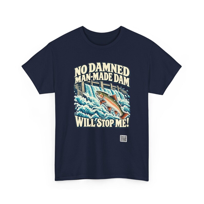 Puede incluir: Una camiseta azul marino con un gr&aacute;fico de un pez saltando sobre una presa con salpicaduras de agua blanca. El texto dice: NO DAMNED MAN-MADE DAM WILL STOP ME! Un peque&ntilde;o c&oacute;digo QR cuadrado est&aacute; impreso en la parte inferior derecha.