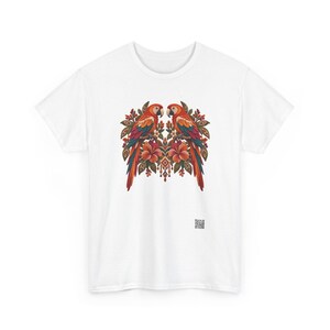 May include: A white short-sleeved t-shirt featuring a central graphic of two symmetrical parrots perched among tropical flowers and foliage in shades of red, orange, and green, with a small square QR code printed near the bottom right.