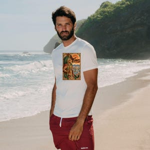 Pu&ograve; includere: Una t-shirt bianca a maniche corte con una stampa grafica rettangolare raffigurante un guerriero azteco con copricapo di piume e un'aquila, abbinata a pantaloncini sportivi bordeaux con coulisse bianca e piccolo testo bianco sulla gamba.