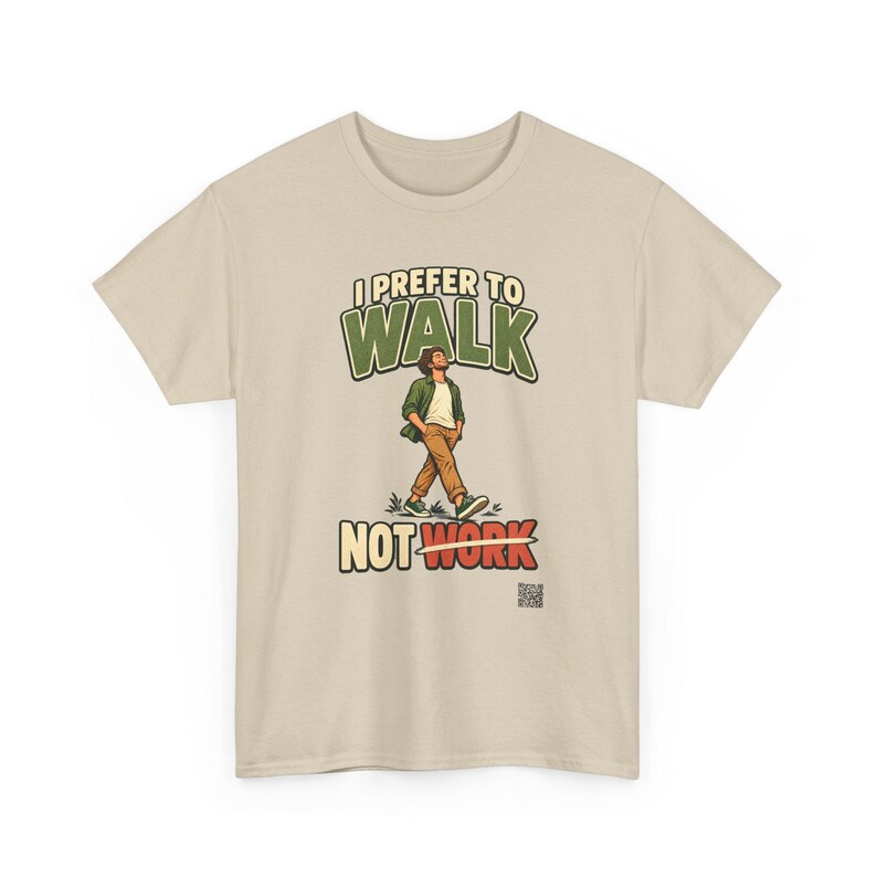 Op de afbeelding: Een beige t-shirt met een afbeelding van een lopend persoon. De tekst luidt I PREFER TO WALK NOT WORK, waarbij het woord WORK is doorgehaald met een horizontale lijn. De persoon draagt een groen overhemd, wit shirt en een bruine broek.