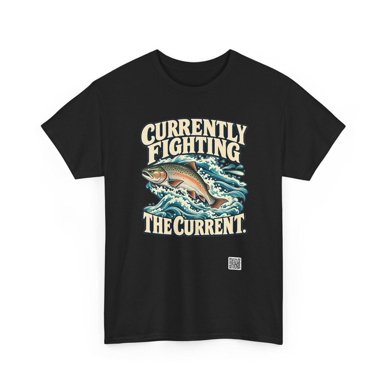 May include: A black t-shirt featuring a graphic of a trout jumping through blue waves. The text above the fish reads "CURRENTLY FIGHTING" and the text below reads "THE CURRENT." A small white square QR code is printed near the bottom right.