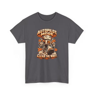 K&ouml;nnte beinhalten: Ein anthrazitfarbenes T-Shirt mit einer Grafik eines wei&szlig;en und orangefarbenen Roboters, der vorw&auml;rts geht. Der Text &uuml;ber dem Roboter lautet AUTOPILOT MODE und darunter steht CLEAR THE WAY! Das Design enth&auml;lt orangefarbene Pfeile und Staubwolken.
