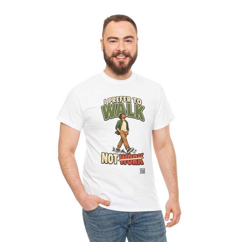 Op de afbeelding: Een wit t-shirt met korte mouwen en een afbeelding van een lopend persoon. De tekst erboven luidt I PREFER TO WALK en de tekst eronder luidt NOT WORK met een potloodafbeelding die het woord WORK doorstreept. Het ontwerp gebruikt groen, bruin en rood.