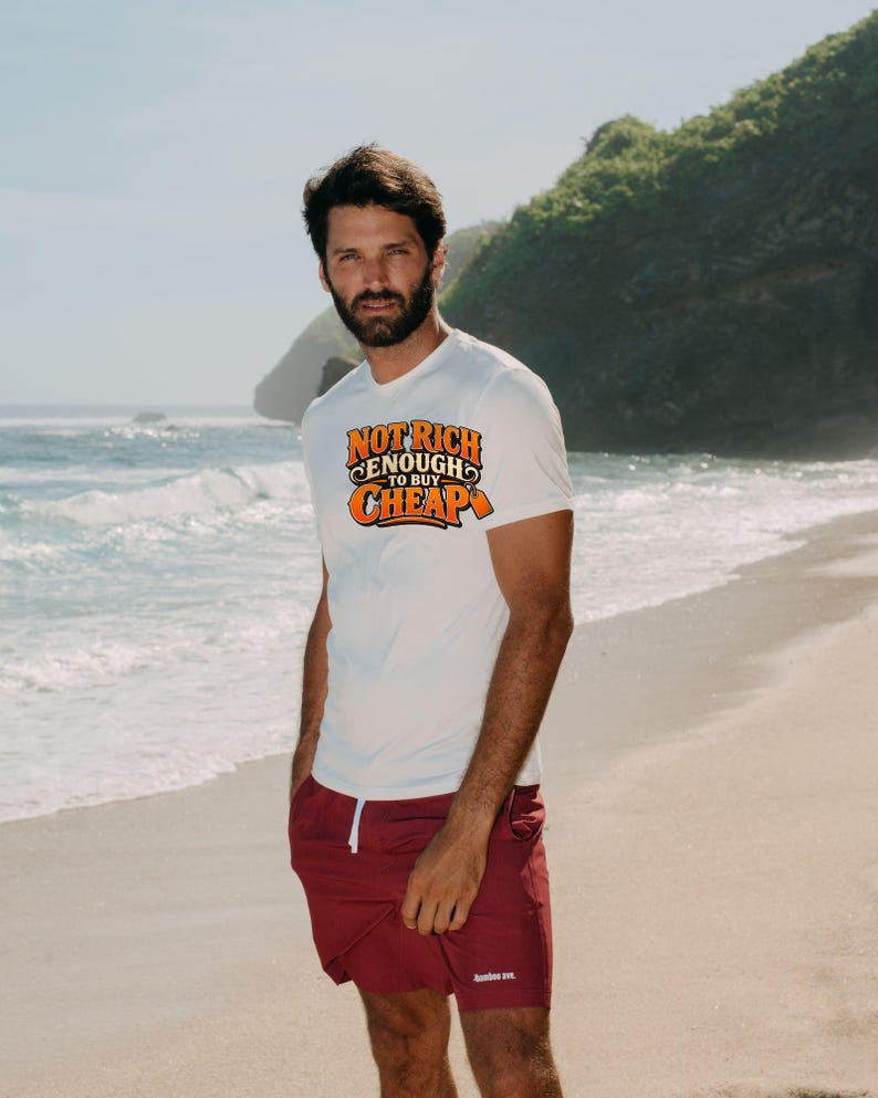 May include: A white short-sleeved t-shirt featuring the orange and black text "NOT RICH ENOUGH TO BUY CHEAP" with a price tag graphic, paired with solid maroon shorts that have a white drawstring and a small white logo on the leg.