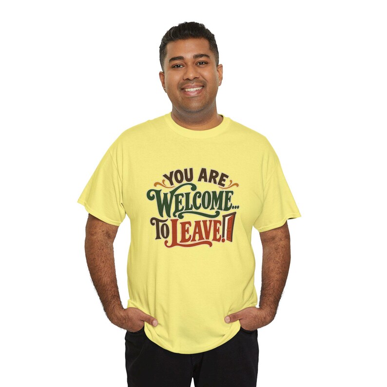 May include: A light yellow short-sleeve t-shirt featuring the text "YOU ARE WELCOME... TO LEAVE!" printed on the front. The word "WELCOME" is in dark green, while "LEAVE" is in a bold, dark red font with a stylized door graphic.