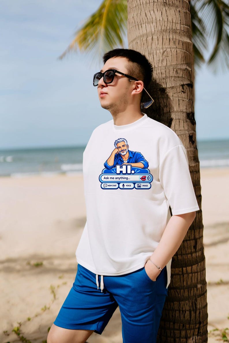 May include: A white short-sleeved t-shirt featuring a graphic of a man in a blue shirt with the text HI. Ask me anything. The graphic includes icons for new chat, voice, and image, along with a red lip icon and a sound wave symbol.