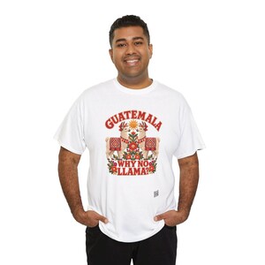 Puede incluir: Una camiseta blanca de manga corta con un estampado gr&aacute;fico de dos llamas con mantas de patrones rojos, un sol y elementos florales. El texto dice GUATEMALA en la parte superior y WHY NO LLAMA? en la parte inferior en letras rojas.