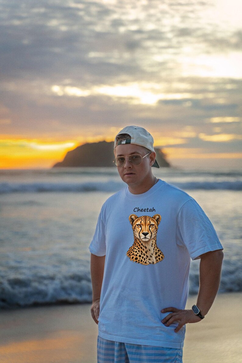 Op de afbeelding: Een wit T-shirt met korte mouwen en een grafische print van de kop en schouders van een jachtluipaard in het midden van de borst, met het woord Cheetah in zwarte letters boven de illustratie.