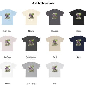 May include: A collection of eleven short-sleeve t-shirts in light blue, natural, charcoal, black, ice grey, dark heather, sand, navy, white, sport grey, and ash. Each shirt features a graphic of a purple robot with the text Autopilot Mode Clear The Way.