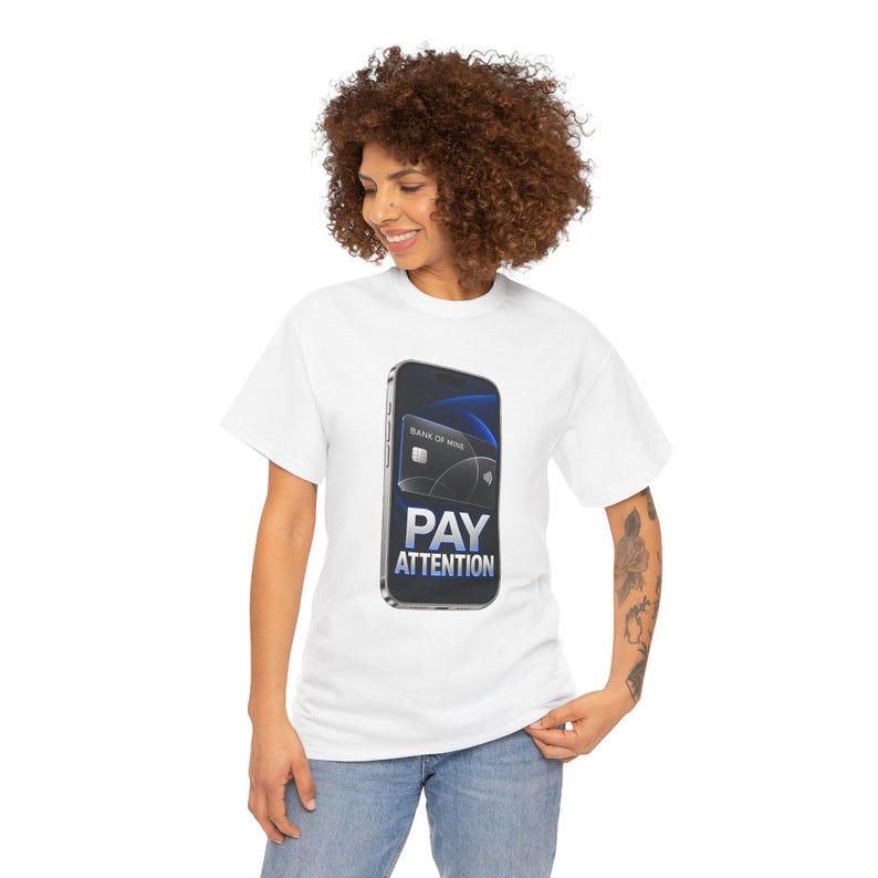 May include: A white short-sleeve t-shirt featuring a graphic of a smartphone displaying a black credit card with the text BANK OF MINE and the words PAY ATTENTION in large white and blue letters centered on the front of the garment.