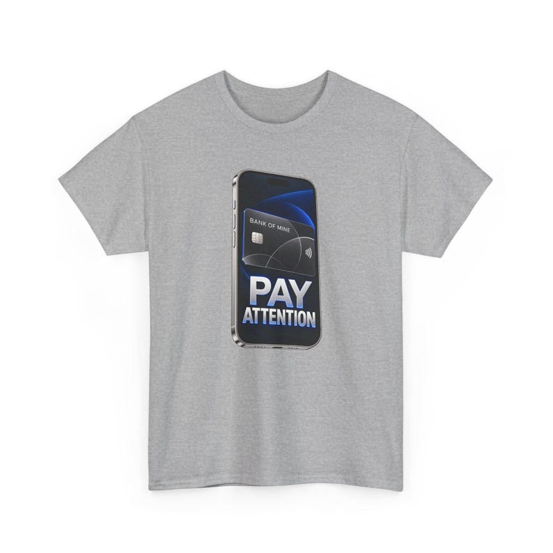 May include: A heather gray t-shirt featuring a graphic of a smartphone displaying a black credit card labeled Bank of Mine and the text PAY ATTENTION in bold white letters. The screen background is a dark blue abstract design.