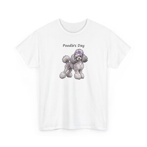 May include: A white short-sleeved t-shirt featuring a graphic of a grey poodle with a purple bow on its head. Above the poodle, the text Poodle's Day is printed in black. The shirt has a crew neckline and a standard fit.